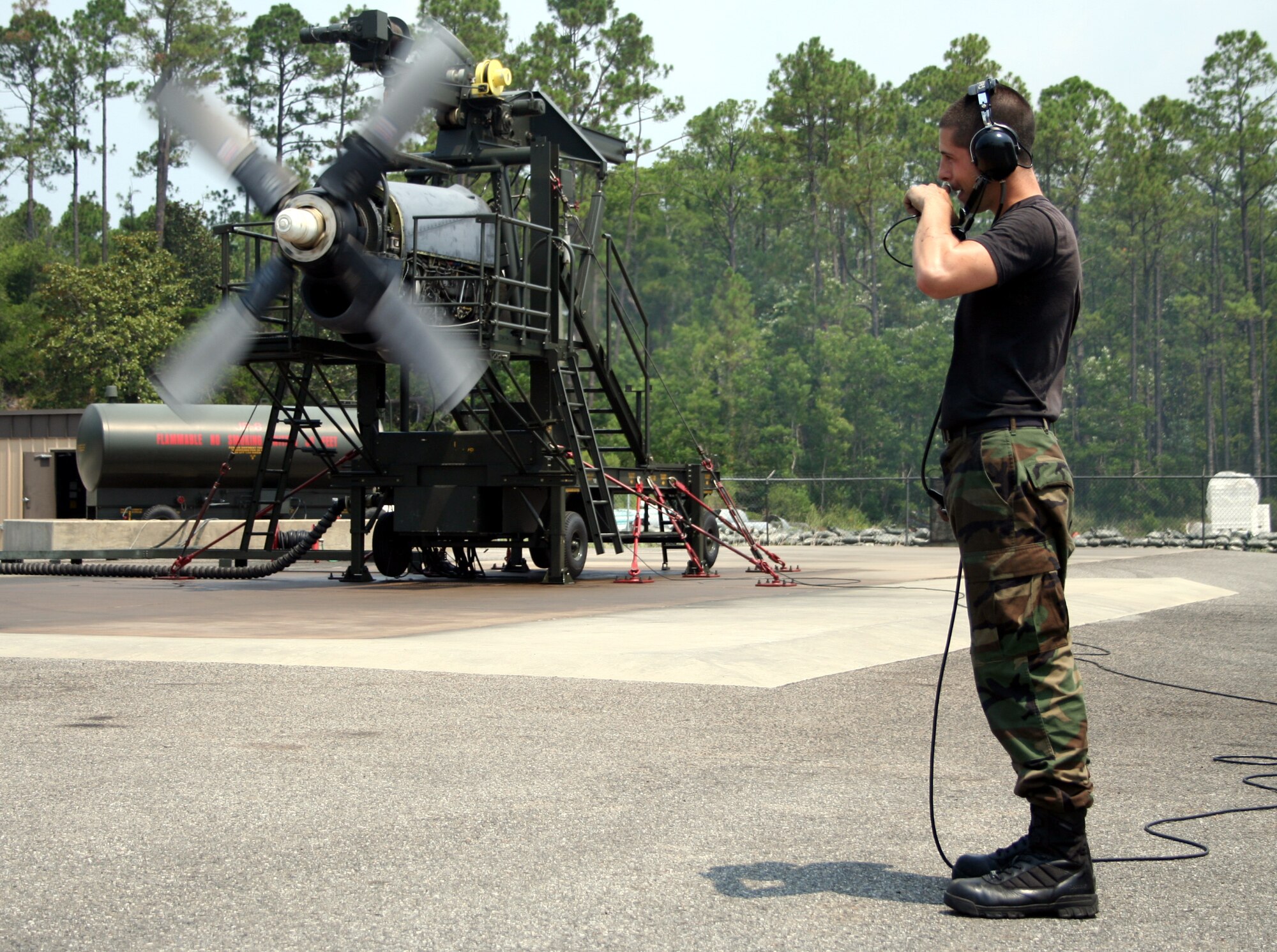 Senior Airman Kyle Gray, 16th Component Maintenance Squadron, relays information during a quick turn for a turbine change on a T-56 engine at the propulsion test cell June 28. (U.S. Air Force Photograph by Dylan Laurie)