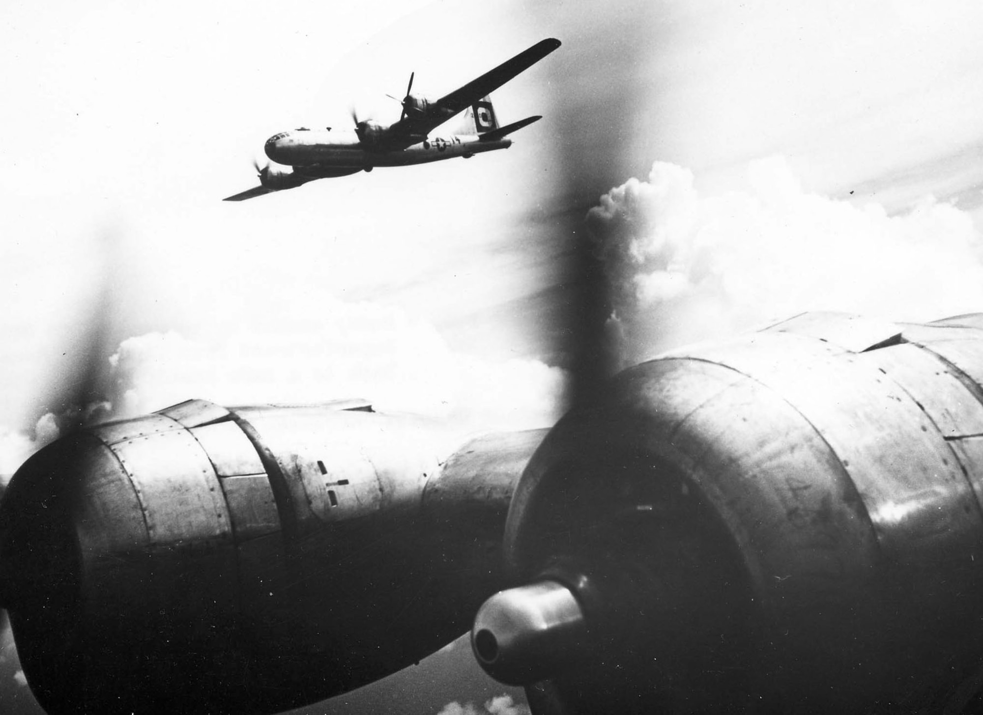 A B-29 with one engine out is escorted to Iwo Jima by another Superfortress. (U.S. Air Force photo)
