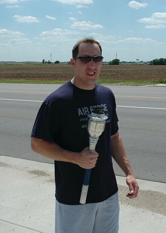 Master Sgt. Gary White holds the torch at the intersection of 63rd and Rock Rd. in Derby, Kan. as he prepares to begin the 931st SF portion of the run.