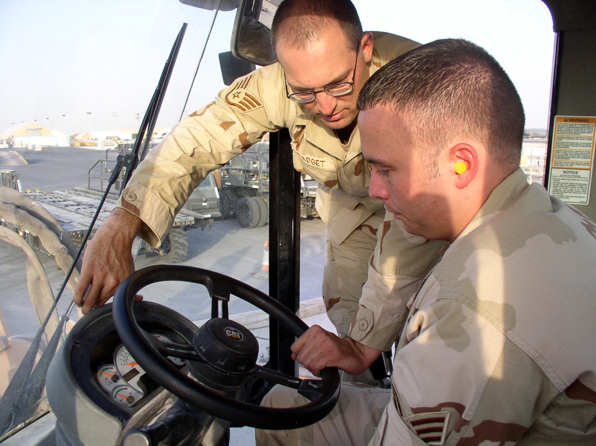 Staff Sgt. John Padget instructs Senior Airman Richard Sanders on the operation of an all-terrain forklift at a forward operating location in Southwest Asia on July 3. The Airmen are with the 379th Expeditionary Operational Support Squadron. (U.S. Air Force photo/Master Sgt. Dutch DeGroot)