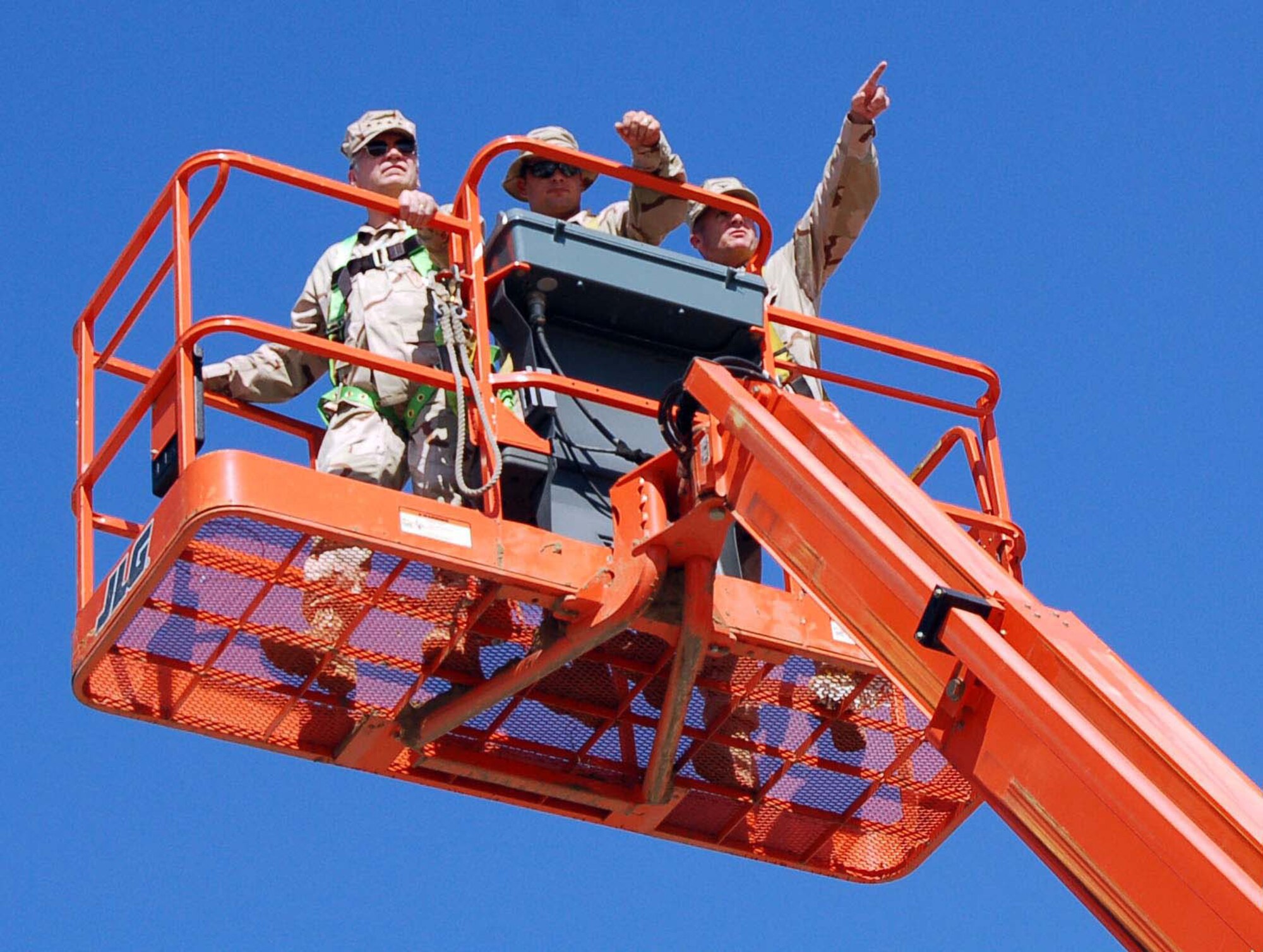 Col. Joel “Scott” Reese (right), 376th Air Expeditionary Wing commander, shows USAFE commander Gen. Tom Hobbins (left) the changes to Manas while high-reach operator Staff Sgt. Dusty Dees, 376th Expeditionary Civil Engineer Squadron, keeps them safe 60 feet in the air during the general’s visit July 5. (U.S. Air Force photo/Capt. Anna Carpenter)
