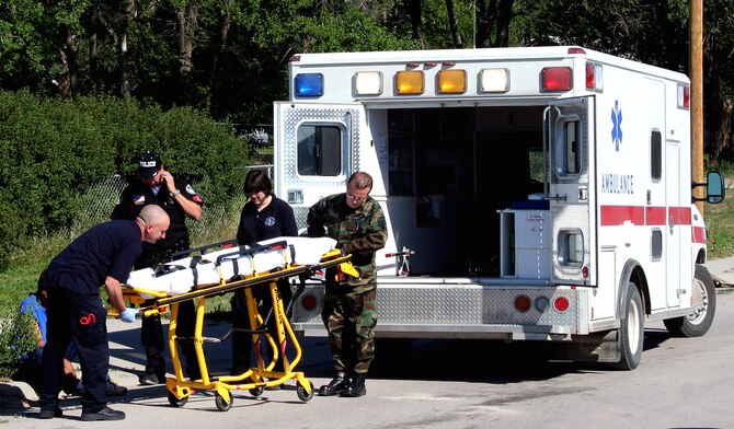 Pine Ridge Indian Reservation, S.D. -- Medical technician Tech. Sgt. Anthony Gallela (right) from the 445th Aeromedical Staging Squadron helps emergency medical technicians prepare to transport a Native American to Pine Ridge hospital for treatment.  A small medical contingency from the 445th ASTS are there for their annual tour training. (U.S. Air Force Reserve photo by Maj. Ted Theopolos)