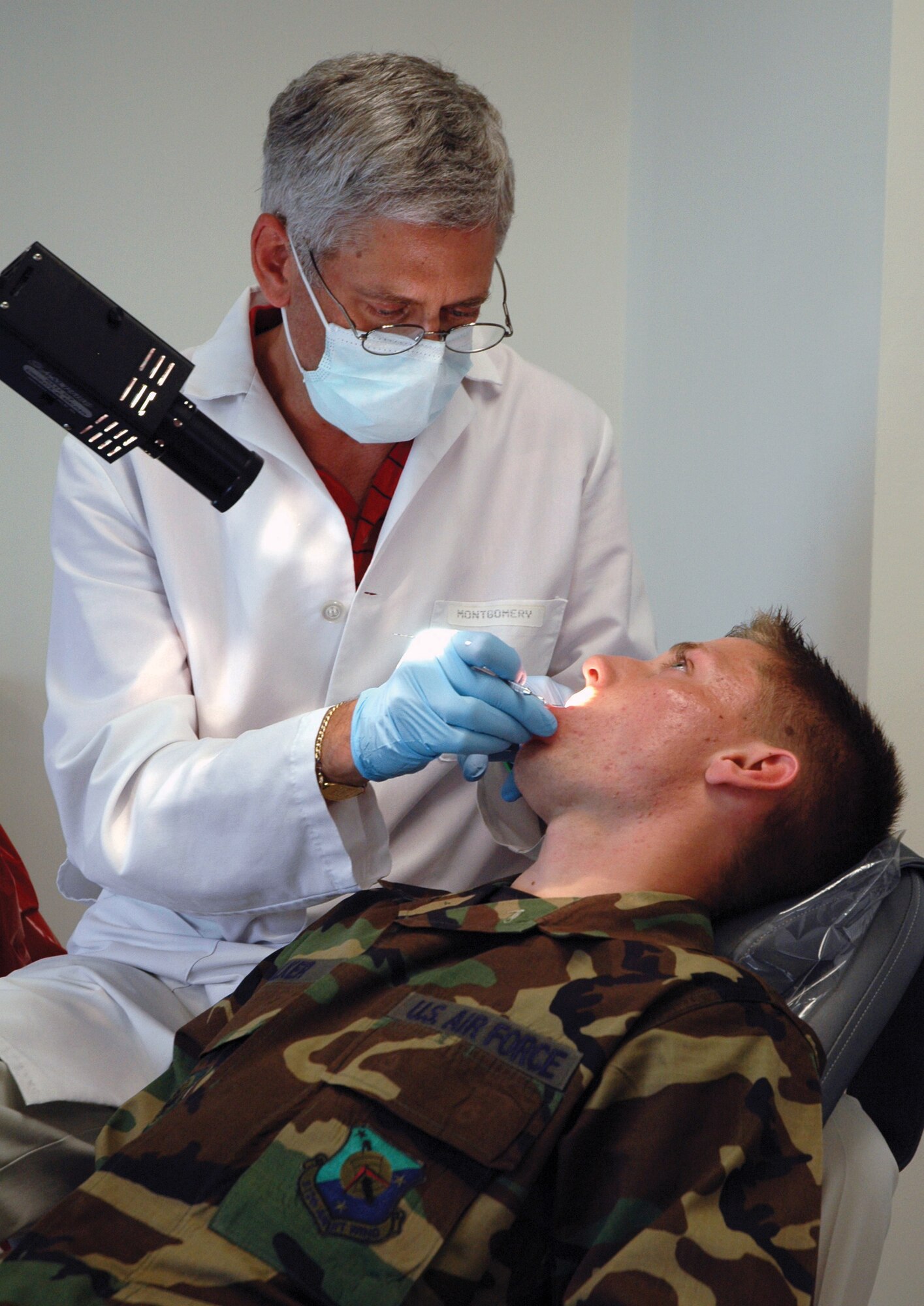 Airman Basic Justin Walker, 512th Aircraft Maintenance Squadron crew chief, gets his teeth examined by Dr. Lawerence Montgomery, a contracted dentist with the FEDS_HEAL program. Dr. Montgomery has been working with the program for almost four years.