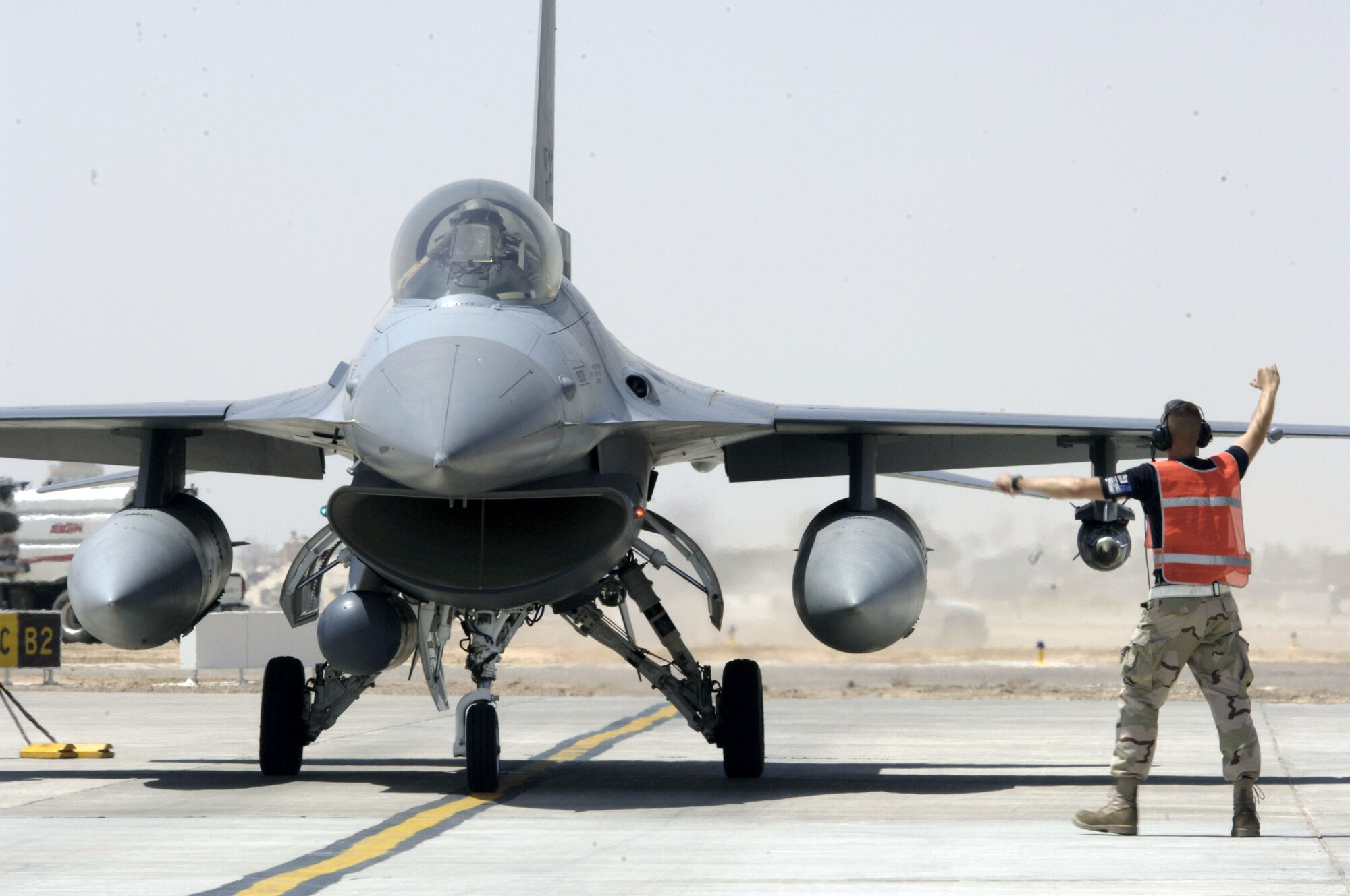 A crewmember marshals an F-16 Fighting Falcon into place for final checks before a mission in support of Operation Iraqi Freedom at Balad Air Base, Iraq, on July 11. (U.S. Air Force photo/Airman 1st Class Andrew Oquendo)