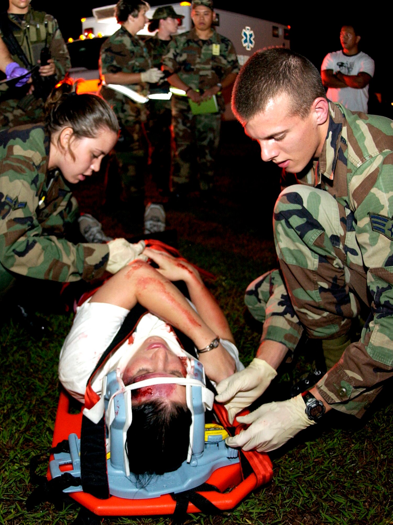 Airman Alina Mata and Senior Airman Stace Reading prepare to transport a person simulating the victim of a vehicle accident at Andersen Air Force Base, Guam, during the Beverly Palm 06-07 exercise on July 10. The exercise is held several times a year to sharpen the mobility and wartime capabilities of Airmen. The Airmen are assigned to the 36th Medical Operations Squadron. (U.S. Air Force photo/Airman 1st Class Miranda Moorer)