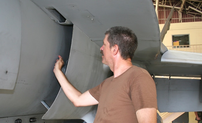 Petty Officer 2nd Class Thomas A. Diamond, Strike Fighter Squadron 97 aviation warfare systems operator and native of Camp Springs, Md., uses a small razor to chip away paint from what he thinks may be a corroded screw.