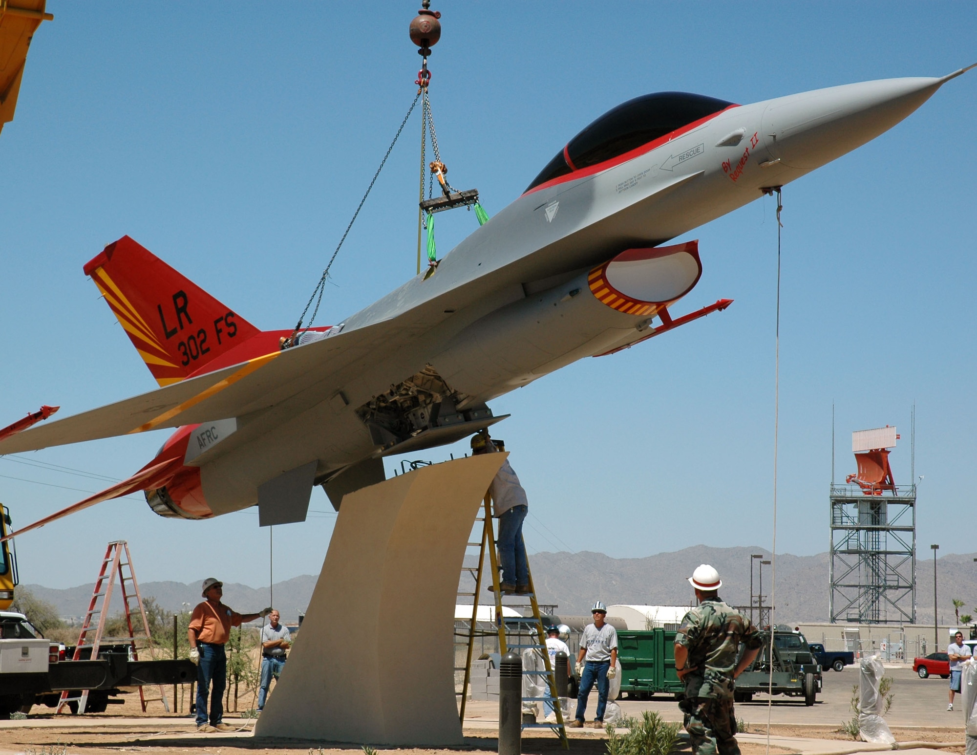 Contractors carefully bolt an F-16 painted in World War II Tuskegee colors onto its pedestal July 11, 2006 at Luke Air Force Base, Ariz. The F-16 will become a static display in front of the 944th Fighter Wing headquarters and is scheduled to be unveiled during a dedication ceremony Aug. 2. The 944th Fighter Wing's 301st and 302nd Fighter Squadrons trace their roots to the Tuskegee Airmen. (U.S. Air Force photo/Staff Sgt. Susan Stout)