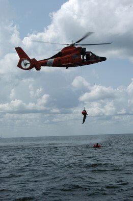 An aircrew member from the 317 AS gets picked up by a Coast Guard helicopter during aircrew survival training.  Pilots and loadmasters from the 315th Operations Group, Charleston AFB, S.C. participated in the one-day event that also included combat survival training. The group went through how to escape, evade and survive, what can be eaten in this situation, how the equipment can be used, and more survival tips. (Photo by Maj. Mark Johnson, USAFR)