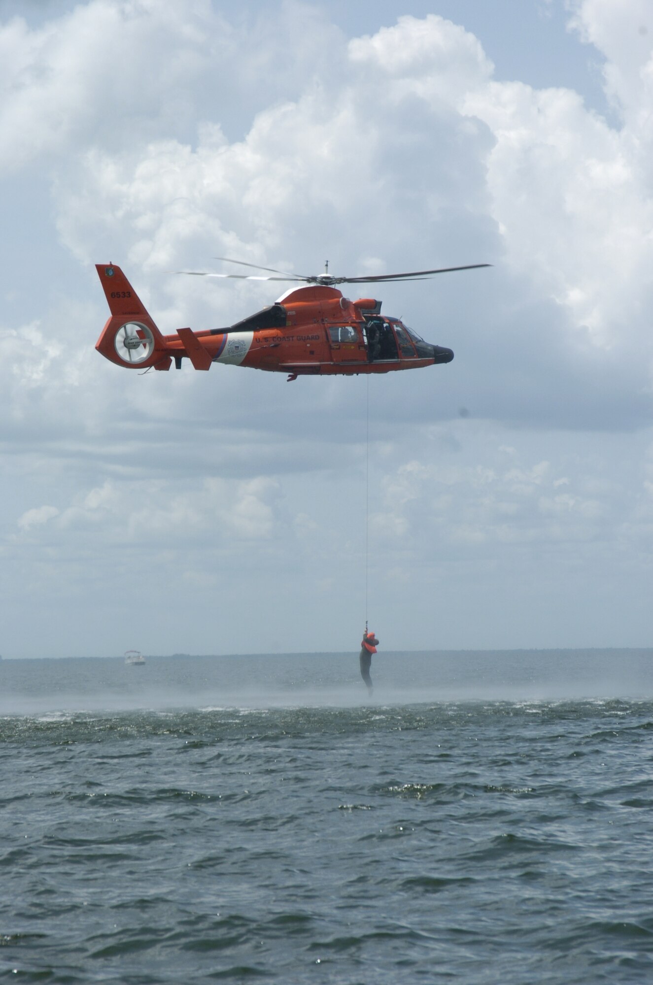 An aircrew member from the 317 AS gets picked up by a Coast Guard helicopter during aircrew survival training.  Pilots and loadmasters from the 315th Operations Group, Charleston AFB, S.C. participated in the one-day event that also included combat survival training. The group went through how to escape, evade and survive, what can be eaten in this situation, how the equipment can be used, and more survival tips. (Photo by Maj. Mark Johnson, USAFR)