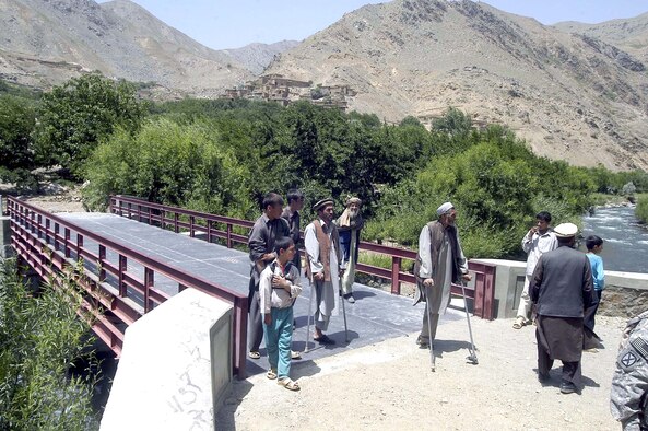 Two Afghan men on crutches cross a newly constructed bridge linking the village of Nawaj and other mountain villages to a main road in the Parwan Province of Afghanistan. The bridge, an initiative of the Parwan government and supported by the U.S. military's Bagram Provincial Reconstruction Team, is the first step in a transportation and flood control project for the Parwan area. (U.S. Air Force photo/Maj. David Kurle)