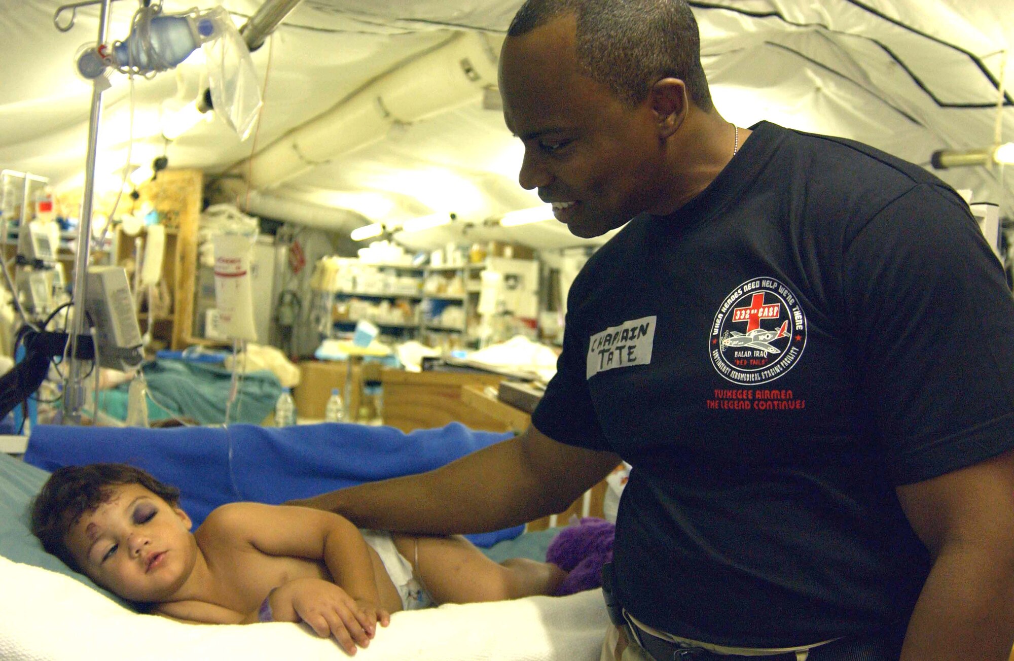 Chaplain (Capt.) Jose Tate comforts an Iraqi child at the Air Force Theater Hospital at Balad Air Base, Iraq, on July 14. Chaplain Tate is specifically trained to provide the hospital's patients and staff spiritual support, services, counseling and sometimes just a friendly ear for those who want to talk. The chaplain is assigned to the 332nd Air Expeditionary Wing. (U.S. Air Force photo/Senior Airman Kerry Solan-Johnson)