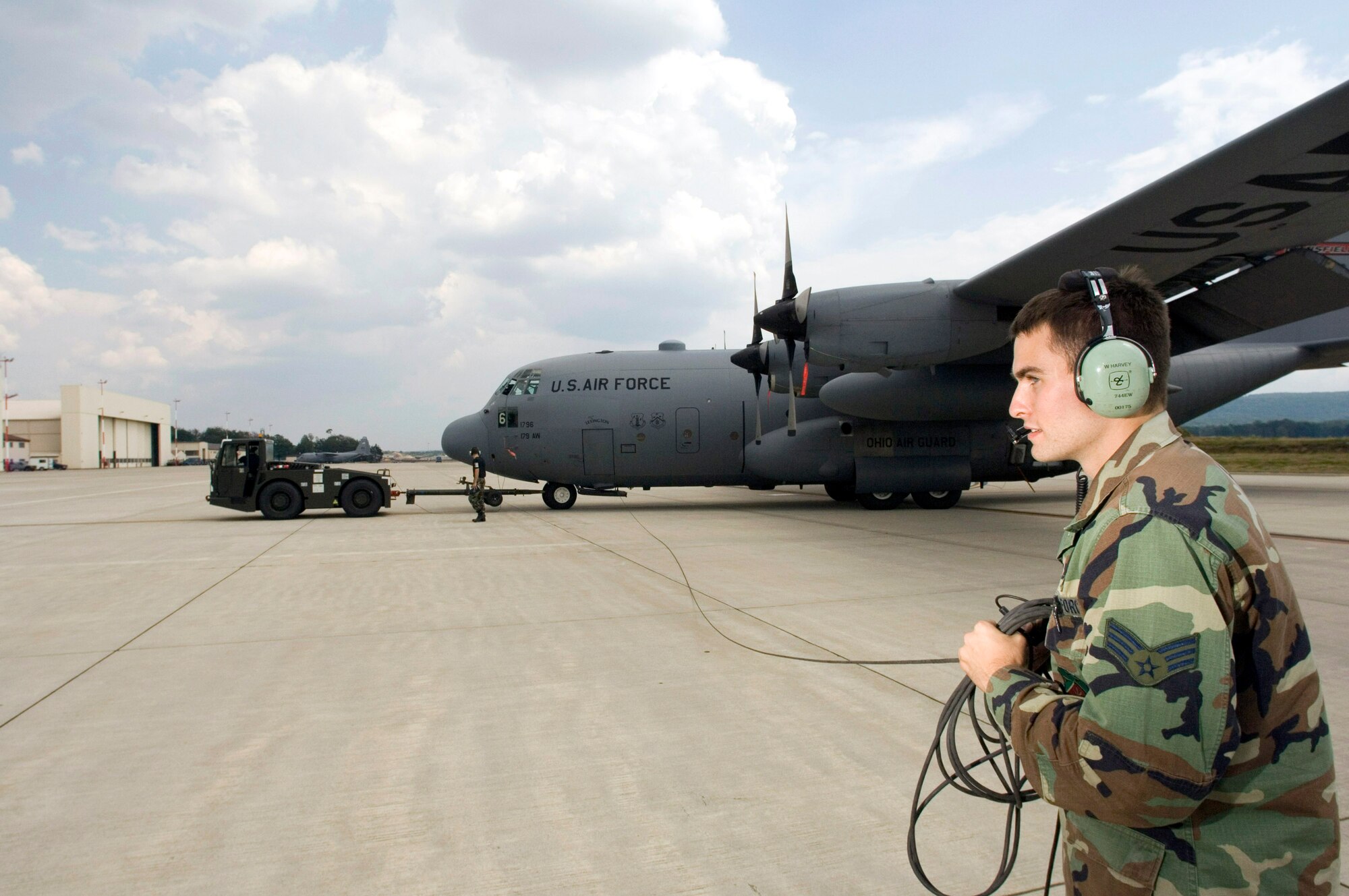Senior Airman William Harvey walks next to the wing of a C-130 Hercules as it is towed to its parking position on Thursday, July 13, at Ramstein Air Base, Germany. Airman Harvey is an electric counter measure specialist on temporary duty for six weeks with the Ohio Air National Guard's 179th Airlift Wing from Mansfield, Ohio. The C-130 unit is flying sorties throughout Europe, Asia and Africa while at Ramstein. (U.S. Air Force photo/Master Sgt. John E. Lasky)