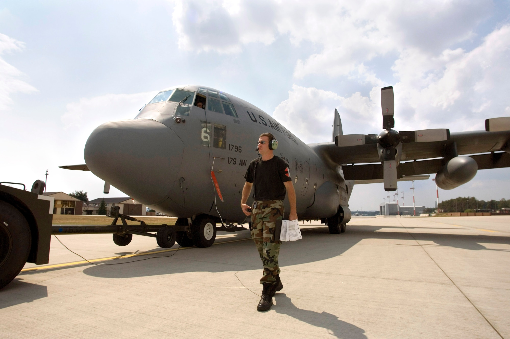 Tech. Sgt. Ken Schonauer walks alongside a C-130 Hercules in tow to its parking position on Thursday, July 13, at Ramstein Air Base, Germany. Sergeant Schonauer, a crew chief, and members of the Ohio Air National Guard's 179th Airlift Wing from Mansfield, Ohio, are on temporary duty for the next six weeks at Ramstein, where they will fly missions throughout Europe, Asia and Africa. (U.S. Air Force photo/Master Sgt. John E. Lasky)