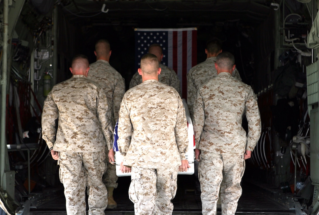 Marines with Camp Taqaddum's personnel retrieval and processing detachment load a flag draped transfer case, used to protect the remains of service members, into a waiting C-130 airplane during an evacuation process, July 19, 2006. An evacuation process is a small remembrance service and the first leg of the journey back to the United States. The mission of PRP is to inventory the personal effects, identify the types of wounds sustained, and prepare the remains for transportation to Dover Air Force Base. "It's a job we do with respect, and it is an honor to give respect to our fallen brothers and sisters," said Marine Cpl. Jose D. James, a serving with the 1st Marine Logistics Group's PRP detachment. The detachment is comprised of mostly reserve Marines from multiple different military occupations.(Official USMC photograph by Cpl. Stephen Holt. 060720-M-0293H-005. Released.)