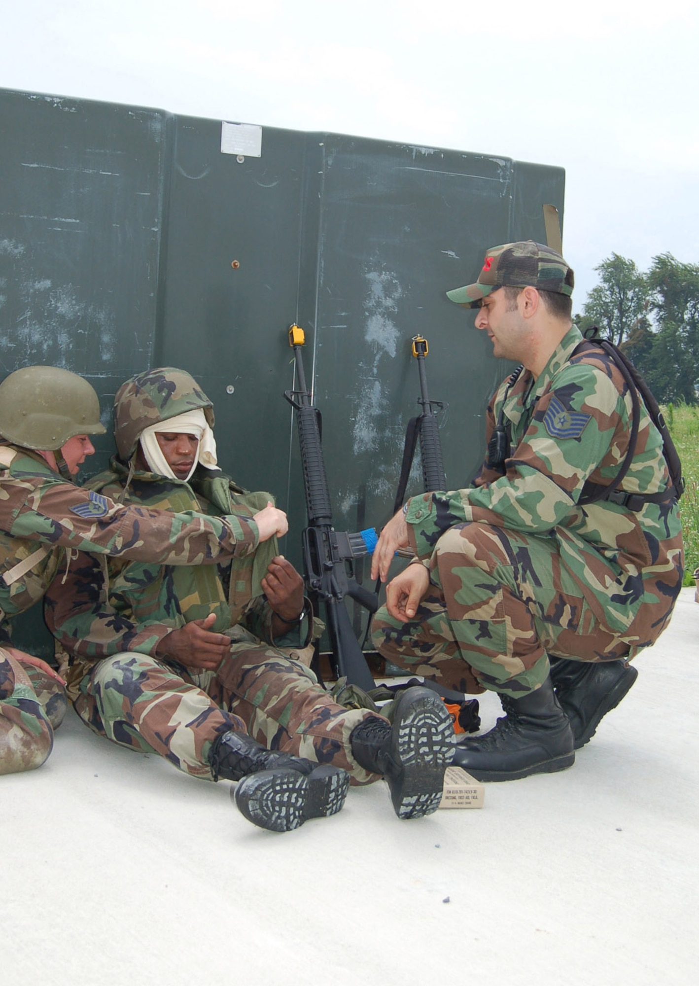 Left to right: Staff Sgt. Leann Ross administers self-aid and buddy care to Staff Sgt. Julio Fareaux, 436th Logistics Readiness Squadron, while cadre instructor Tech. Sgt. Andrew Springstead, 436th Aeromedical-Dental Squadron, monitors their actions during Expeditionary Combat Skills Training field training. Both cadre instructors and trainees come from various Air Force specialties to learn the concepts of integrated base defense. ECST consists of a minimum of 19 hours of training divided between classroom instruction and “hands-on” field training. (U.S. Air Force photo/Staff Sgt. James Wilkinson)