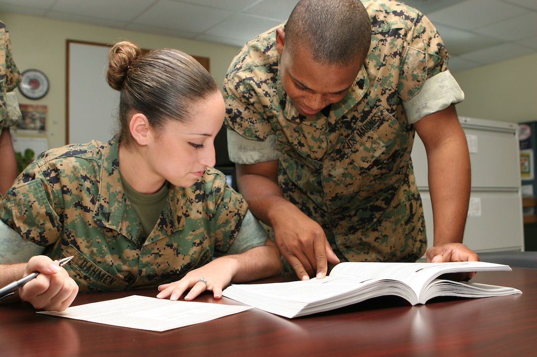 Lance Cpl. Mercedes P. Dahmen (left), Headquarters and Service Company clerk, II Marine Expeditionary Force Headquarters Group, II MEF, listens as Sgt. Dwayne T. Philibert, field mess specialist, II MHG, points out information in the voting manual. Unit Voting Assistance Officers are ready and able to help Marines who may be unsure of state voter registration requirements.