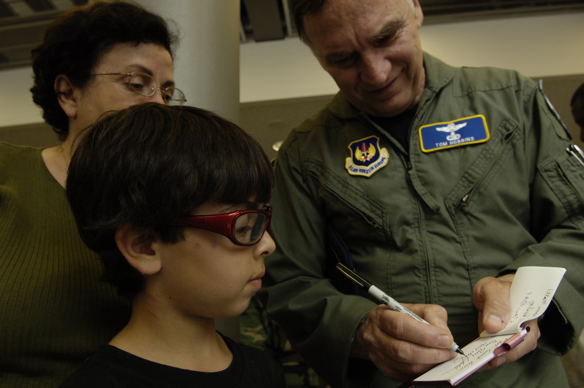 Gen. Tom Hobbins, commander of U.S. Air Forces in Europe, signs an autograph for Danni Chmait, American departee, at Ramstein Air Base, Germany on July 22, 2006. After landing at Ramstein, 101 American departees from Lebanon wait in the passenger terminal to travel on to the continental U.S. by means of a C-17 Globemaster aircraft. (U.S. Air Force photo by Staff Sgt. Stacy L. Pearsall)(released)

