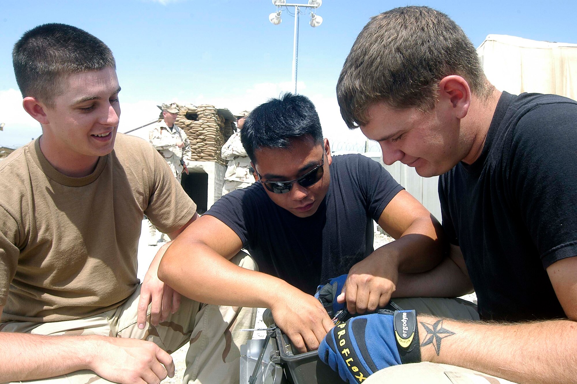 From left, Airman 1st Class Derek Schmidt, Senior Airman Jayson Hernandez and Airman 1st Class Steven Land, electricians for the 755th Prime BEEF engineers at Bagram Airfield, wire an oudoor light fixture.  The three electricians are part of an eight-person teem upgrading the electrical wiring at a field hospital run by the Egyptian military at Bagram. The electrical project is one of many done by the Prime BEEF team nearing the end of its six-month deployment from Kadena Air Base, Japan. (US Air Force photo/Maj. David Kurle)