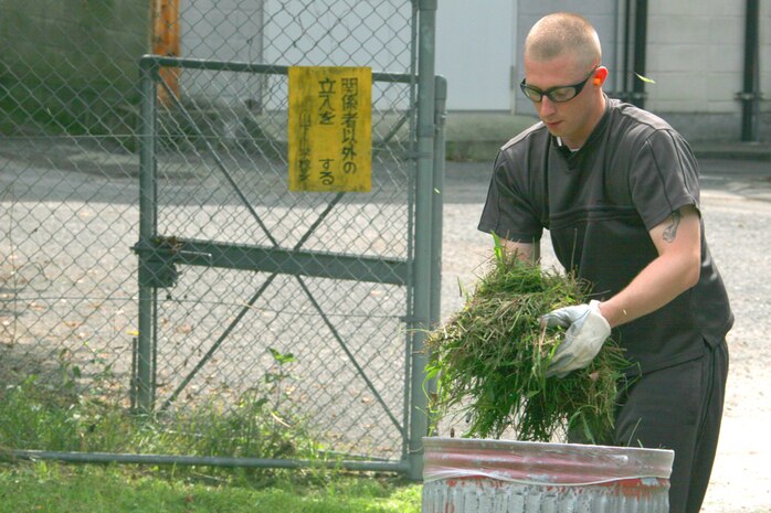 Petty Officer 2nd Class Anthony C. Anderson, Seabee and Portland, Ore., native, places a pile of cut grass in a trash bag during the Seabees Saturday clean up near the Nishiki River. The Seabees accumulated approximately 50 bags of loose foliage after their day was done.