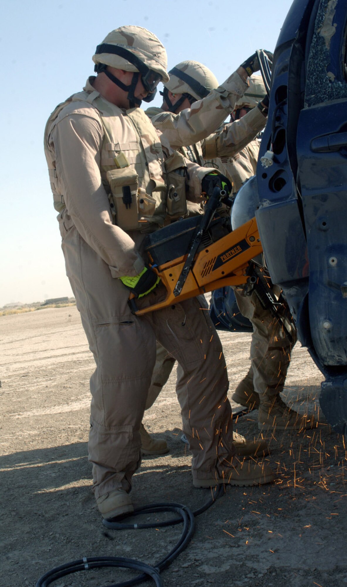 (From left) Staff Sgt. Patrick Peterson, Tech. Sgt. Jeremy Kennedy and Senior Airman Adam Little cut into a vehicle frame to open the door and remove a simulated crash victim at Ali Base, Iraq. The scenario was part of their training for the Rescue Air Mobility Squad. (U.S. Air Force photo/Staff Sgt. Rasheen Douglas) 
