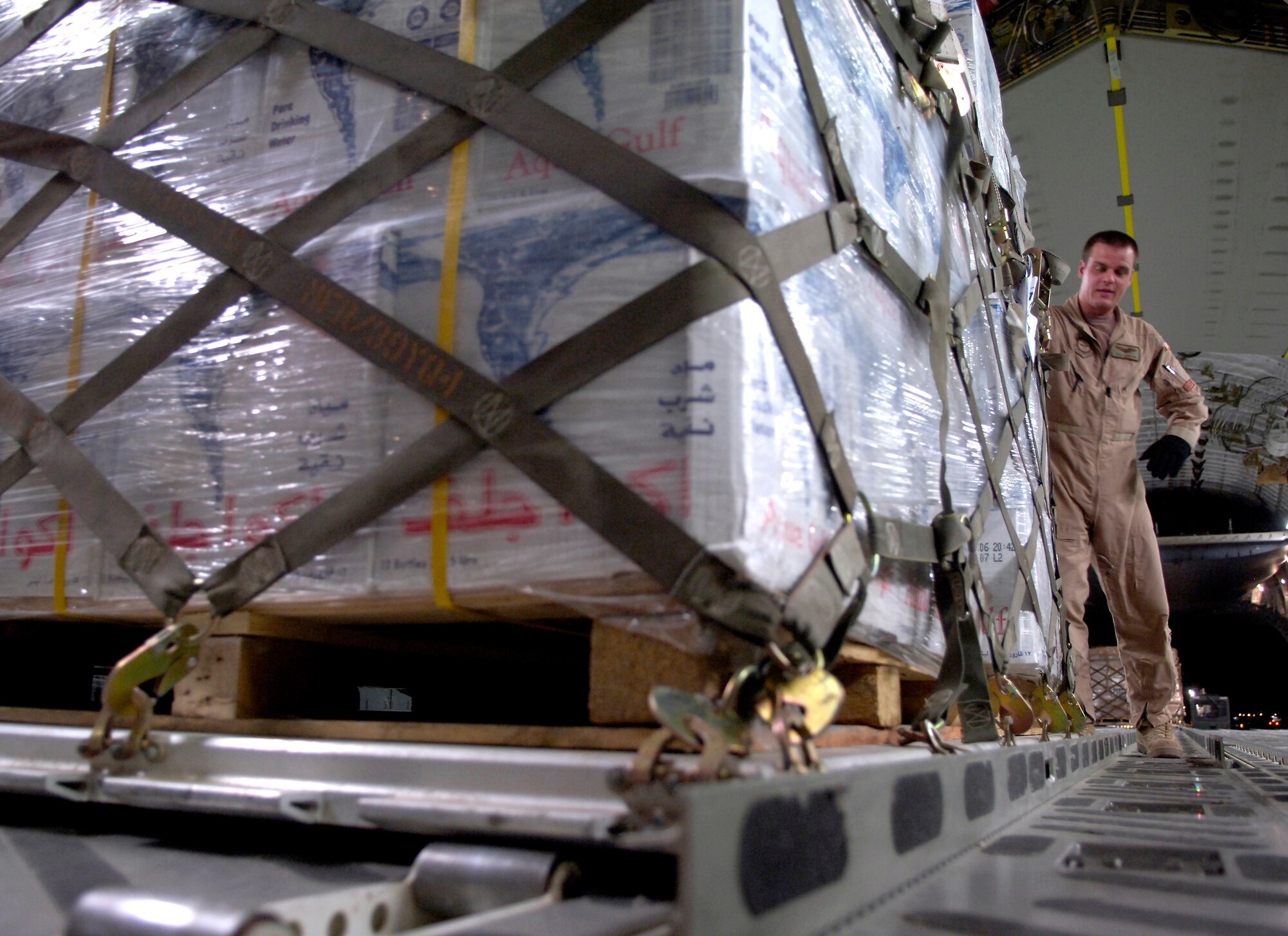 First Lt. Kyle Hamilton pushes a pallet of water into place as the crew loads the plane in Southwest Asia before departing for Cyprus on July 22. C-17 Globemaster III crews from the 816th Expeditionary Airlift Squadron are filling their cabins with pallets of supplies such as water, Meals, Ready to Eat and cots for the American citizens leaving Lebanon. This C-17 transported 17 pallets, about 64,000 pounds, of cargo to Cyprus on this mission. Lieutenant Hamilton is a co-pilot with the 816th EAS. (U.S. Air Force photo/Senior Airman Brian Ferguson) 