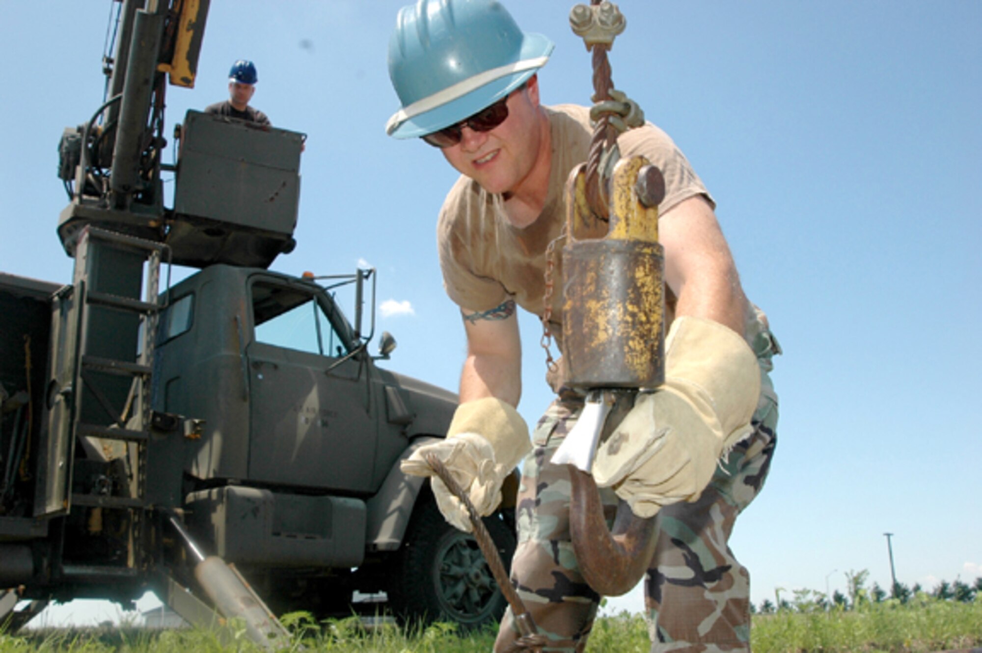 GRISSOM AIR RESERVE BASE, Ind -- Master Sgt. James Nichols, NCOIC of the electrical section,  waits in the bucket of the truck as Staff Sgt. Howard Campbell, an electrical systems craftsman, hooks a piece of cable cinched around a telephone pole to a hook so the pole can be raised into position and set. (U.S. Air Force photo/Senior Airman Jonathan Jones)