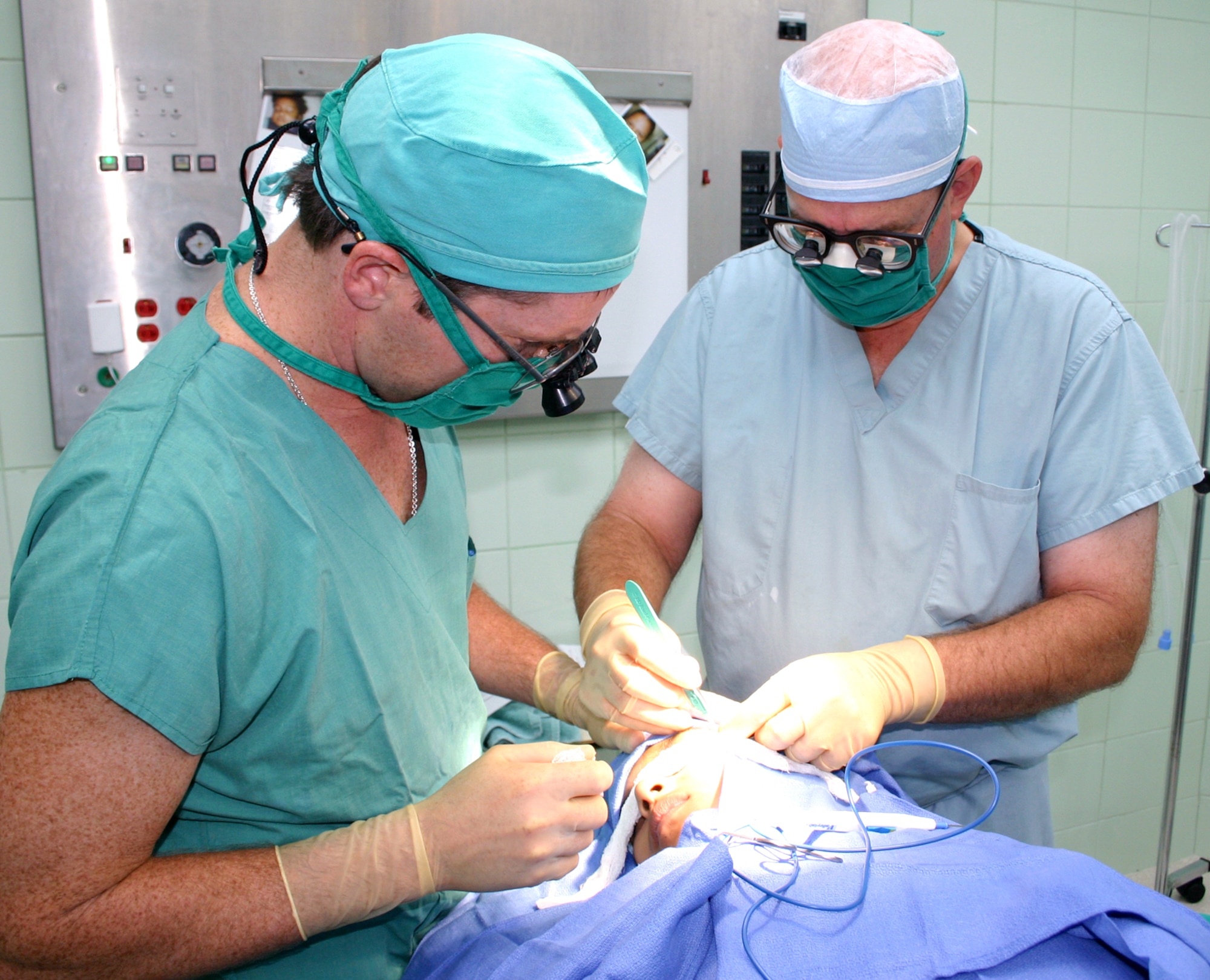 Maj. (Dr.) Matthew Talarczyk (left) and Col. (Dr.) Charles Hardin perform a scar revision procedure on a 15-year-old Ecuadorian girl in Esmereldas, Ecuador. The two surgeons are members of the Medical Readiness Training Exercise team from Wilford Hall Medical Center at Lackland Air Force Base, Texas. (U.S. Air Force photo/2nd Lt. David Herndon) 
