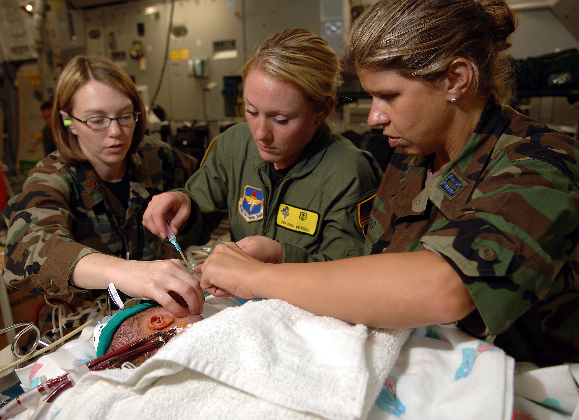 (From left) Capt. Jeanette Gonzalez, Senior Airman Kris Vensel and Capt. Karen Long administer medications to 3-day-old Stuart Parker aboard a C-17 Globemaster III on July 21. An Extracorporeal Membrane Oxygenation team comprised Air Force and Army medical specialists from the Wilford Hall Medical Center at Lackland Air Force Base, Texas, flew to San Juan, Puerto Rico, to transport Stuart to San Antonio for more advanced care. Captain Gonzalez is a neonatal doctor, Airman Vensel is a respiratory therapist and Captain Long is a neonatal intensive care nurse at Wilford Hall Medical Center. (U.S. Air Force photo/Master Sgt. Scott Reed)