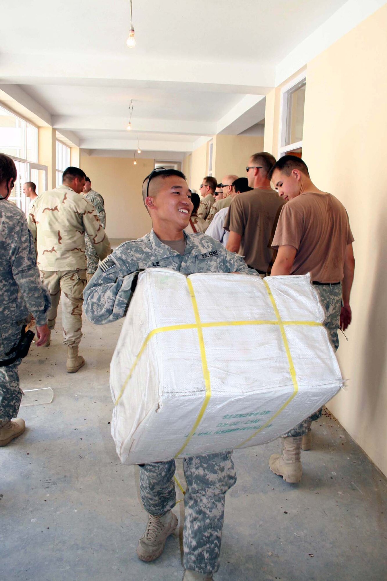 Army Reserve Staff Sgt. Leon Le, deployed from the 364th Civil Affairs Brigade in Portland, Oregon, carries a bale of tea -- part of 10 tons of humanitarian assistance supplies -- delivered to the Shutol District Center in the Panjshir Province July 23. Sergeant Le is a member of the Panjshir Provincial Reconstruction Team. Shutol is the southernmost district in the province and was the fourth HA drop by the Panjshir PRT since June. All HA drops have been done in close coordination with the needs set forth by the provincial government. (US Air Force photo/Capt. Joe Campbell)
