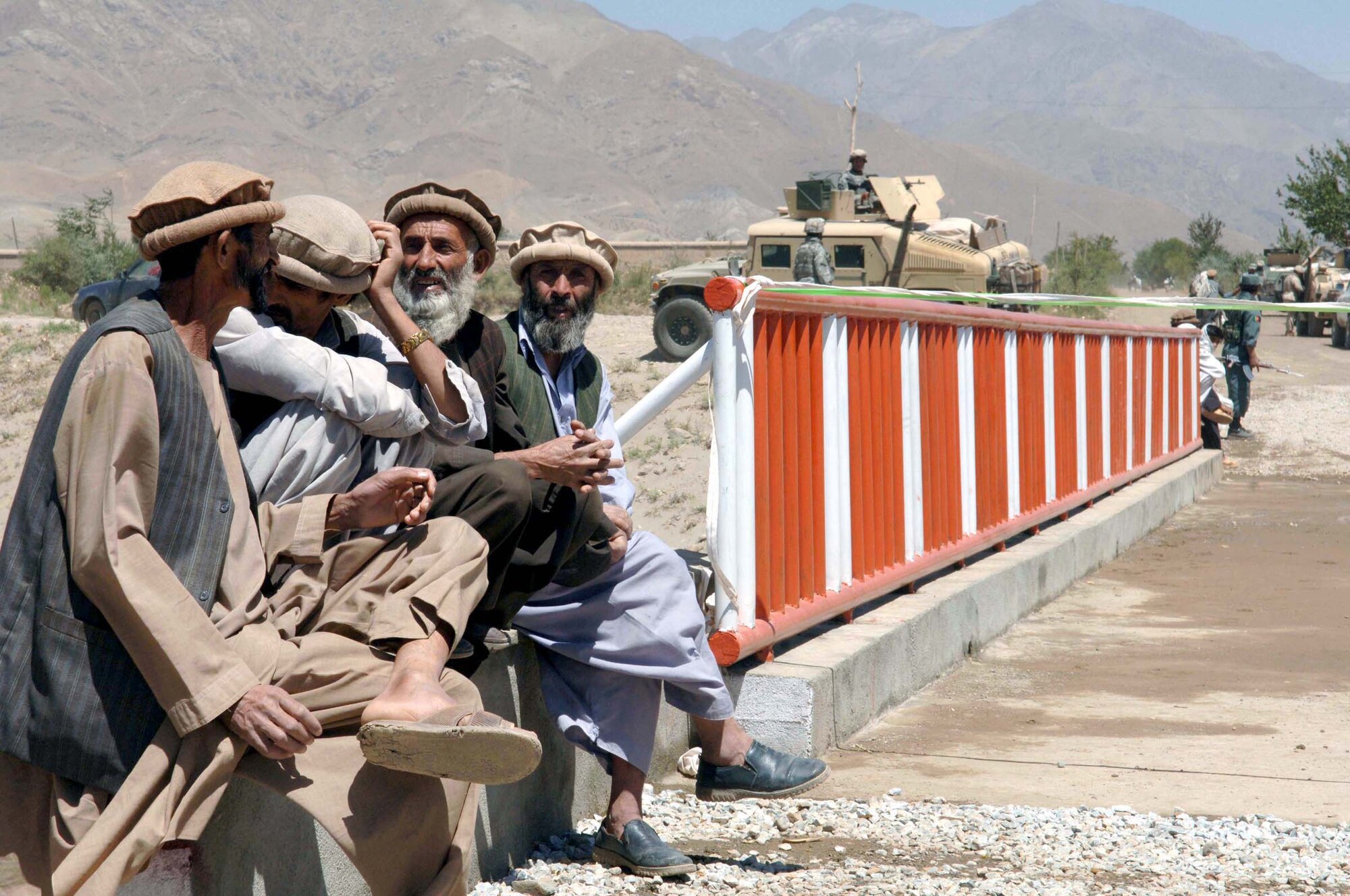 JABAL SARAJ, Afghanistan -- Afghan men visit while waiting for their governor to cut the ribbon across the bridge. The Bagram Provincial Reconstruction Team helped improve a road and build a two-way bridge here.
