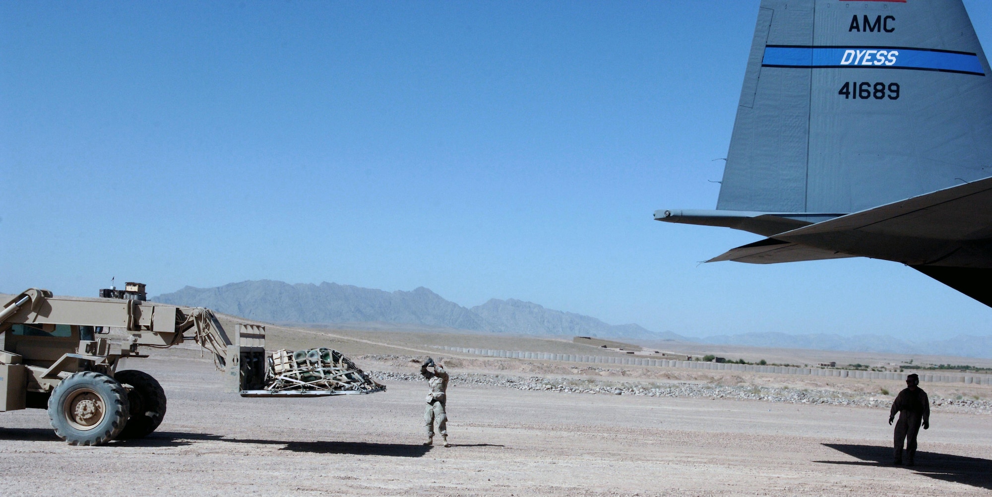 Tech. Sgt. Philip Lester directs a forklift as it carries a cargo pallet to an awaiting C-130 Hercules.  Sergant Lester is assigned to an Army unit in Tarin Kowt, Afghanistan.