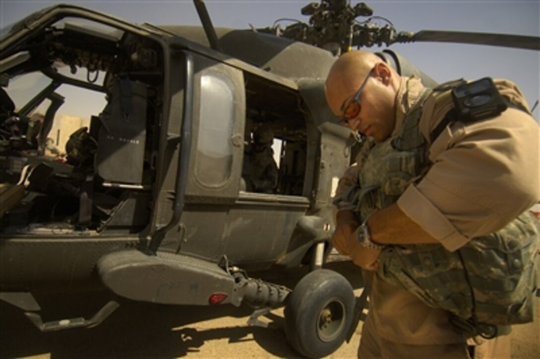 U.S. Army Chief Warrant Officer 2 Gideon Brent, a UH-60A Black Hawk helicopter pilot for Forward Support Medical Team 1, puts on his flight gear upon receiving the order to launch a "nine line," an urgent medical evacuation mission, after a vehicle-borne improvised explosive device injured approximately 50 people in Sinjar, Iraq, July 7, 2006. Brent is from the 542nd Medical Company (Air Ambulance) out of Fort Campbell, Ky.