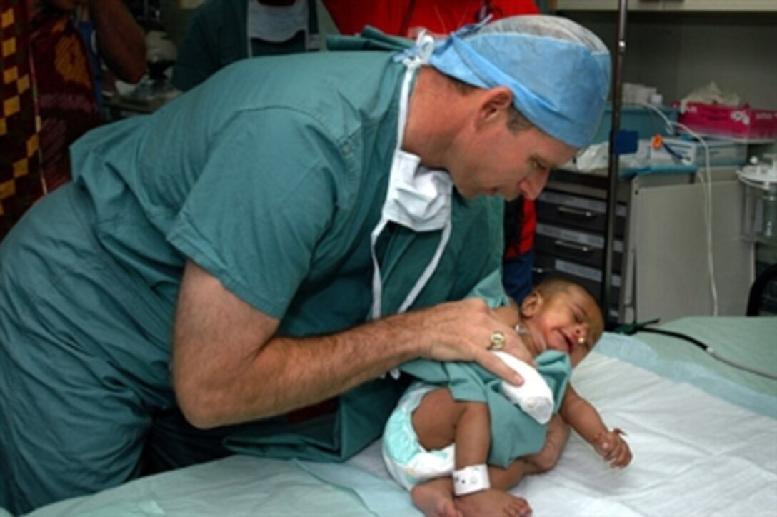 Medical Treatment Facility Commanding Officer Capt. Joseph L. Moore, aboard the U.S. Military Sealift Command hospital ship USNS Mercy, returns a child to the recovery room, July 4, 2006. The child received corrective surgery for a cleft lip during the ship's visit to provide humanitarian and civic assistance to the people of Bangladesh. 