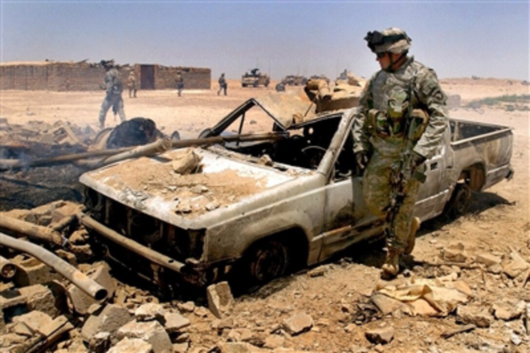 U.S. Army Pfc. Zachary McDaniel of the 1st Squadron, 33rd Cavalry Regiment, 3rd Brigade Combat Team, 101st Airborne Division, looks over a bombed-out car after a firefight with insurgents during Operation Starlit, July 6, 2006. The nine-day mission was conducted in the Salah-Ad-Din providence of Iraq. 