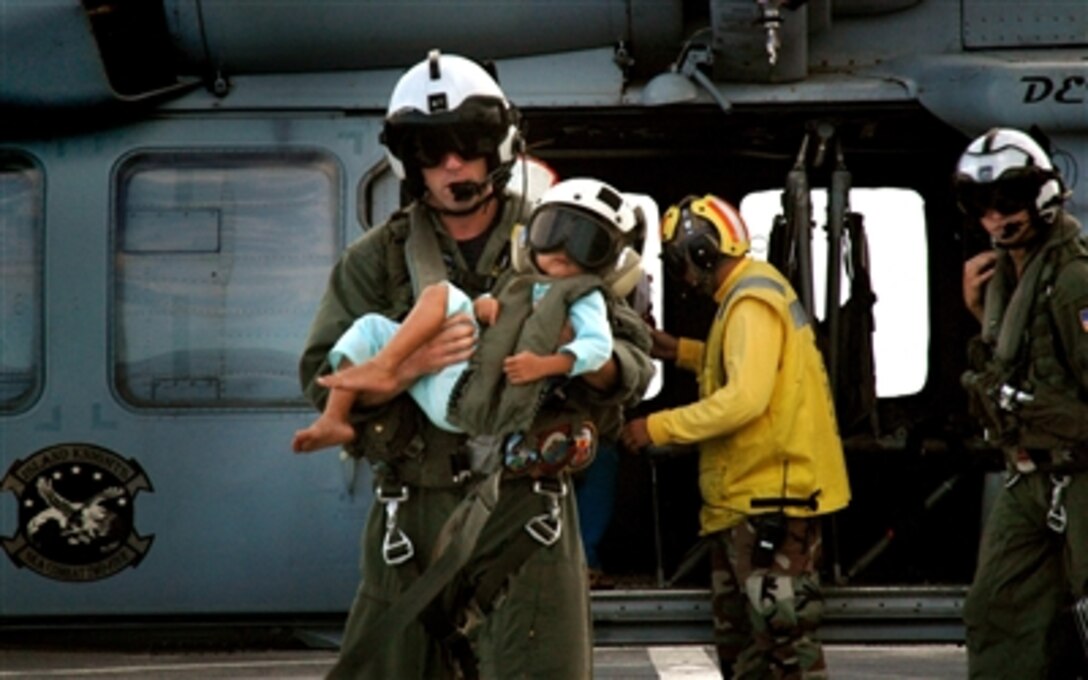 U.S. Navy Petty Officer 3rd Class Thomas Baker carries a young child from an MH-60H Seahawk helicopter aboard the U.S. Military Sealift Command hospital ship USNS Mercy off the coast of Simeulue Island, Republic of Indonesia, July 15, 2006. The child will be one of many to receive medical care during the Mercy’s visit to Indonesia on a scheduled humanitarian mission. 