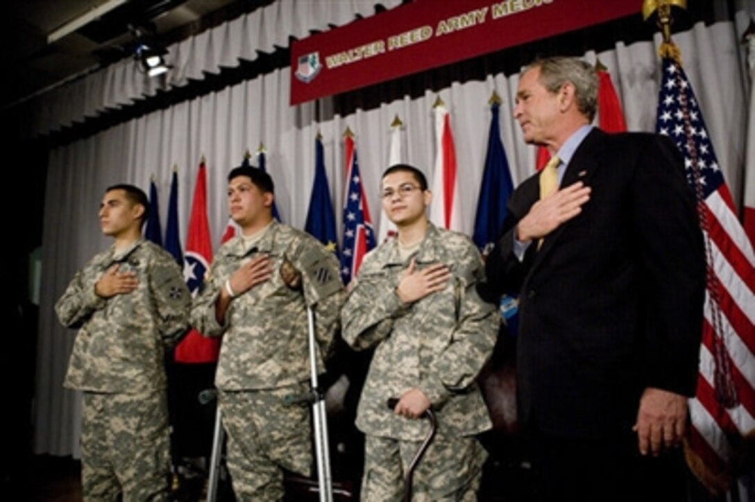 President George W. Bush recites the Pledge of Allegiance Monday, July 24, 2006, at Walter Reed Army Medical Center in Washington, D.C., joining newly sworn-in American citizens, Specialist Sergio Lopez, 24, of Bowlingbrook, Ill., left, Specialist Noe Santos-Dilone of Brooklyn, N.Y., center, and Private First Class Eduardo Leal-Cardenas of Los Angeles, Calif., during their naturalization ceremony. 
