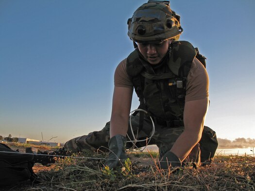 BARBER?S POINT, Hawaii -- Senior Airman Julius Valenzuela of the Hawaii Air National Guard's 297th Air Traffic Control Squadron buries a glow stick attached to fishing line as part of an exercise at Barber's Point, Hawaii, on 25 July, 2006.  The glow stick is part of the base defense program, and will serve to alert scouts to intruders during the night. (US Air Force photo by Tech. Sgt. Chris Vadnais)