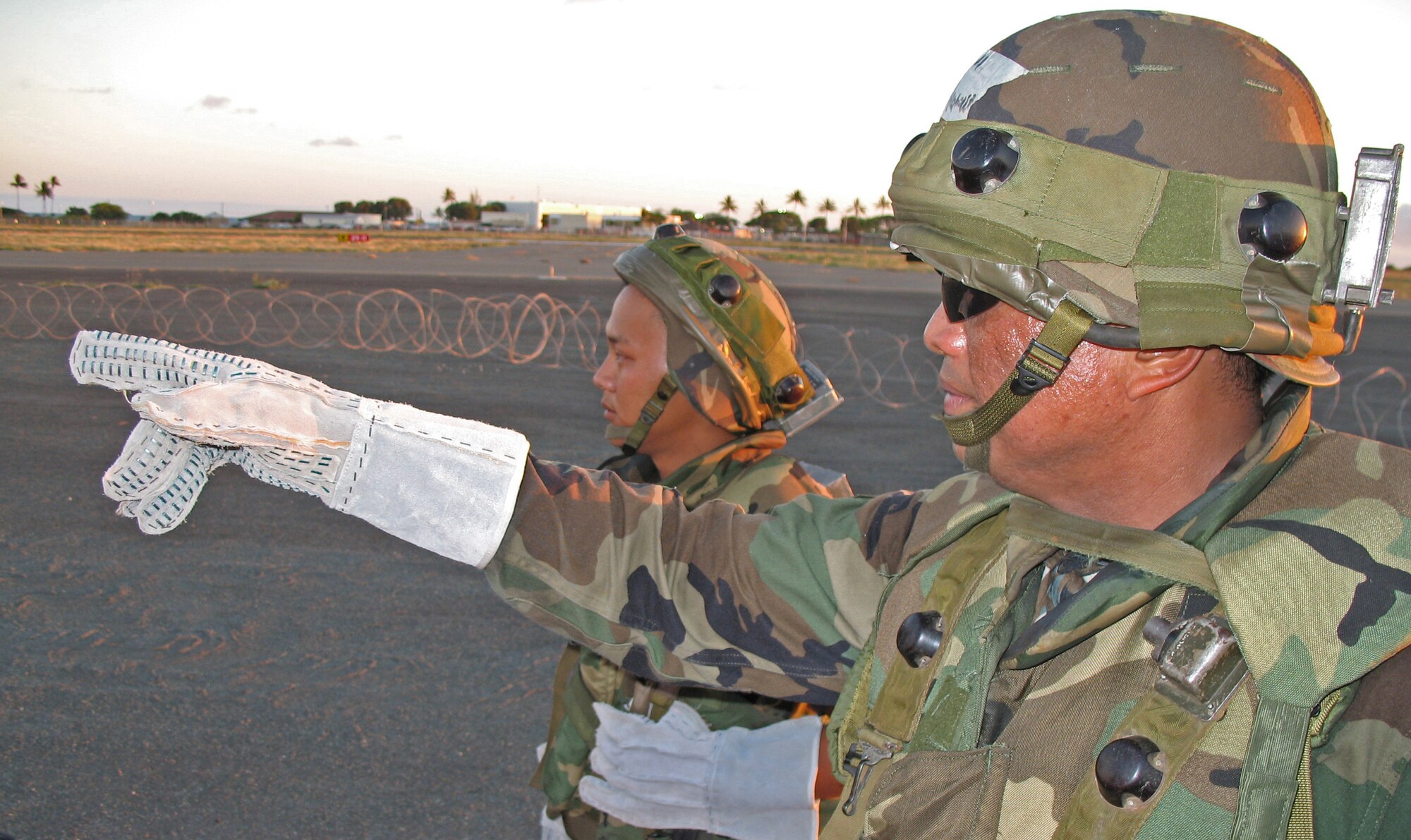 BARBER?S POINT, Hawaii -- Master Sgt. Rodney Arguilles points out holes in the razor wire fence as he and Senior Airman Pat Takenishi discuss base defense strategies during an exercise at Barber's Point, Hawaii, on 25 July, 2006.  Both Airmen are with the Hawaii Air National Guard's 297th Air Traffic Control Squadron.  (US Air Force photo by Tech. Sgt. Chris Vadnais)