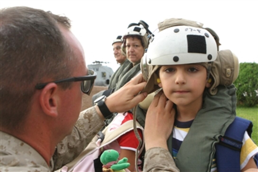 A U.S. Marine of the 24th Marine Expeditionary Unit assists an American citizen with his cranial helmet before he helicopters out from the American Embassy in Beirut, Lebanon, on July 22, 2006. At the request of the U.S. Ambassador to Lebanon and at the direction of the Secretary of Defense, the United States Central Command and elements of Task Force 59 are assisting with the departure of U.S. citizens from Lebanon.