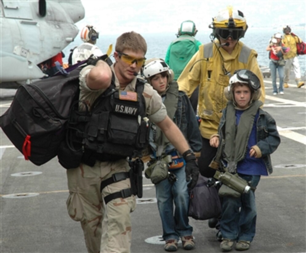 U.S. Navy sailors assist two young American citizens as they arrive on the flight deck of the USS Trenton (LPD 14) as the ship operates off the coast of Lebanon on July 21, 2006. At the request of the U.S. Ambassador to Lebanon and at the direction of the Secretary of Defense, the United States Central Command and elements of Task Force 59 are assisting with the departure of U.S. citizens from Lebanon. The Trenton is an amphibious transport which is used to carry and land Marines, their equipment and supplies by embarked air cushion or conventional landing craft, amphibious vehicles, helicopters or vertical take off and landing aircraft. 
