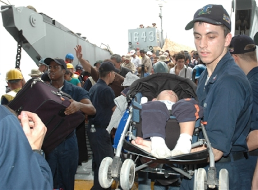 A U.S. Navy sailor carries a sleeping child in a stroller from a landing craft utility boat to the USS Trenton (LPD 14) as the ship operates off the coast of Lebanon on July 21, 2006. At the request of the U.S. Ambassador to Lebanon and at the direction of the Secretary of Defense, the United States Central Command and elements of Task Force 59 are assisting with the departure of U.S. citizens from Lebanon. The Trenton is an amphibious transport which is used to carry and land Marines, their equipment and supplies by embarked air cushion or conventional landing craft, amphibious vehicles, helicopters or vertical take off and landing aircraft.