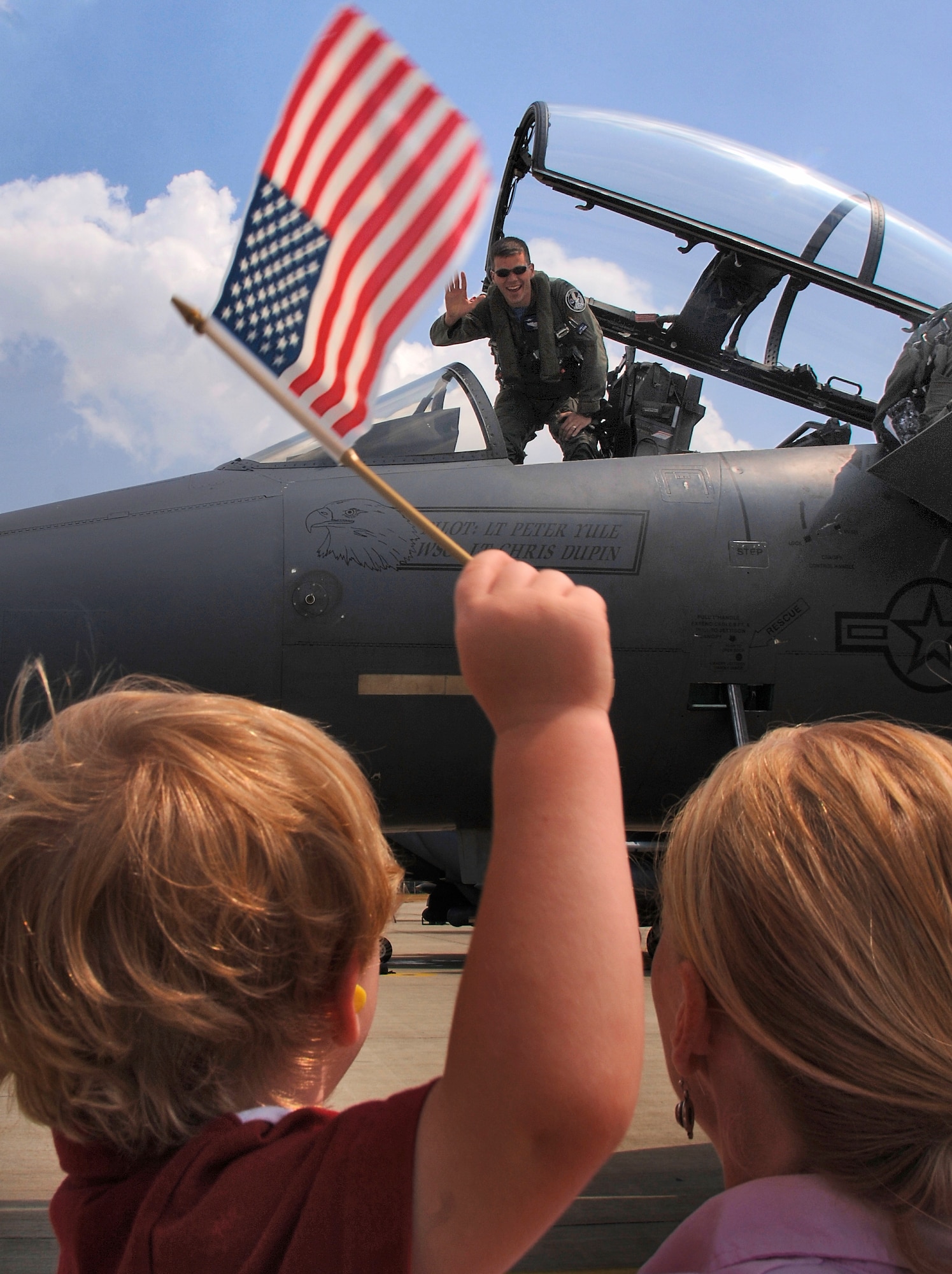 Aimee Hemmingsen, right, holds her 3-year-old son Mitchell as he waves an American flag while waiting for his father, Capt. Martin Hemmingsen, to climb down from his F-15E Strike Eagle on his return to Royal Air Force Lakenheath, England, on Friday, July 28. The captain, of the 492nd Fighter Squadron, and other members of the 48th Fighter Wing deployed to Graf-Isnatievo Air Base, Bulgaria, where they took part in exercise Immediate Response, which began July 17. The joint, trilateral exercise also included the Bulgarian and Romanian militaries and U.S. Soldiers. The Airmen practiced ground attack and air-to-air tactics. (U.S. Air Force photo/Master Sgt. Lance Cheung)