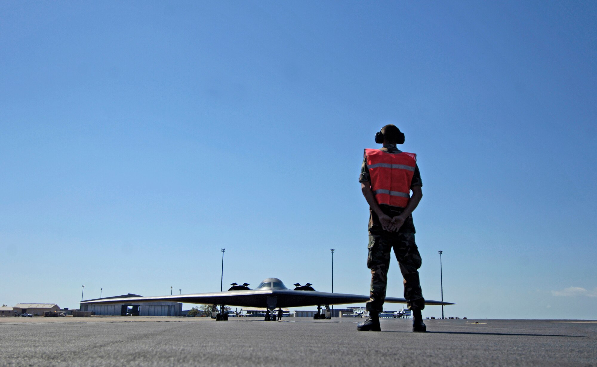Staff Sgt. Jeremy Hord waits to marshal a B-2 Spirit stealth bomber from its parking spot at Royal Australian Air Force Base Darwin on July 27 during exercise Green Lightning. The exercise tests U.S. capabilities and provides operational familiarity in the region for the Pacific bomber presence while also serving to enhance relations with the Australians. Sergeant Hord is from the 509th Aircraft Maintenance Squadron at Whiteman Air Force Base, Mo.  (U.S. Air Force photo/Tech. Sgt. Shane A. Cuomo)