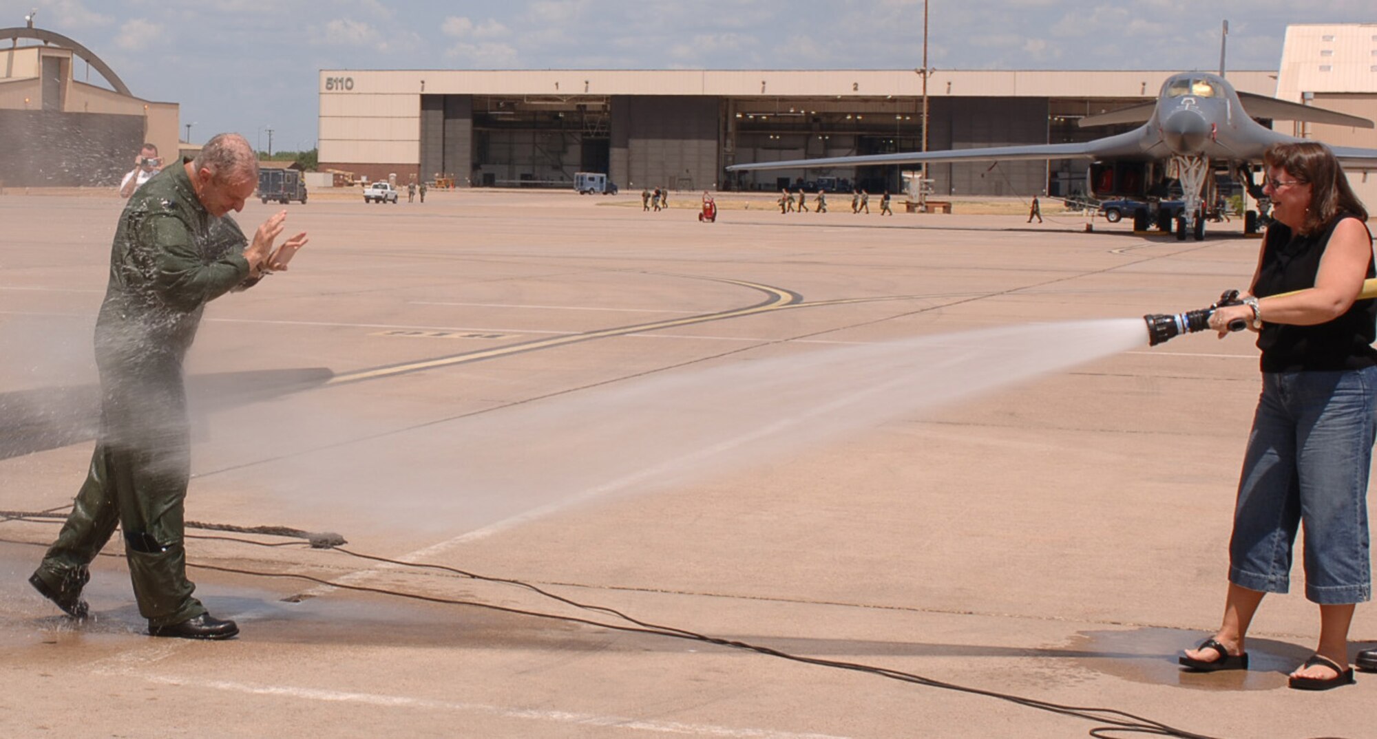 Tanya sprays down her husband, Col. Garrett Harencak, after his final flight as the 7th Bomb Wing commander July 21.