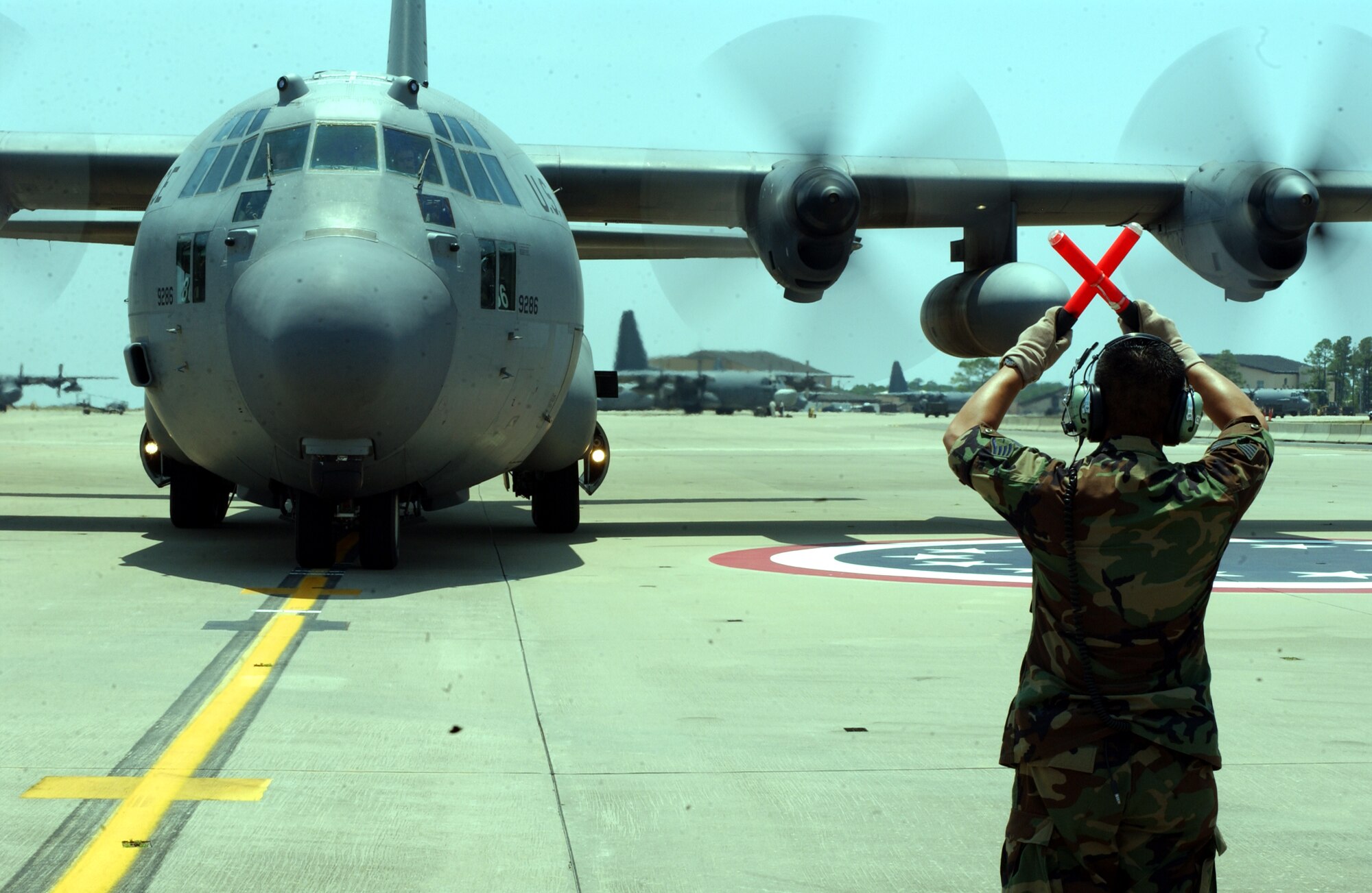 Staff Sgt. Somkit Chittakone, 16th Aircraft Maintenance Squadron and the aircraft's honorary crew chief, guides Hurlburt's first MC-130W to a stop here July 21.  (U.S. Air Force Photograph by Senior Airman Andy Kin)