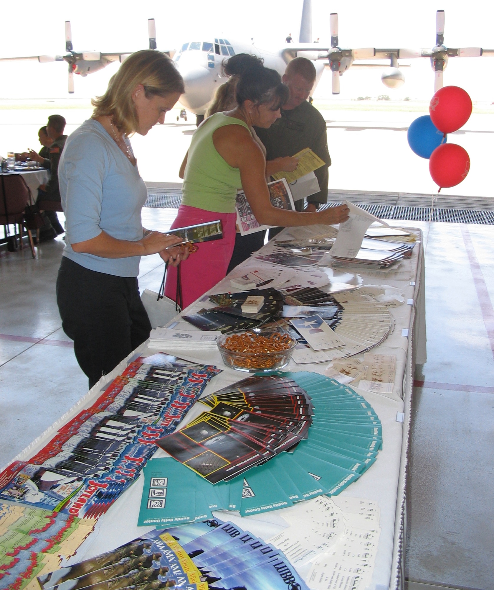 Brandy Hewins (front), wife of Capt. Chad Hewins, 15th Special Operations Squadron, and Connie Morreale, wife of Lt. Col. Mike Morreale, 16th Aircraft Maintenance Squadron commander, pick up brochures and other information about Cannon Air Force Base and its surrounding areas during their visit to the base July 20. (U.S. Air Force Photograph by Lt. Amy Cooper)