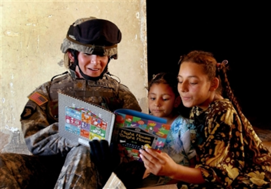 Army Maj. Jennifer Bailey reads a book to Iraqi girls during a humanitarian mission near Contingency Operating Base Speicher, Tikrit, Iraq, on July 23, 2006. Bailey is from the 402nd Civil Affairs Battalion.