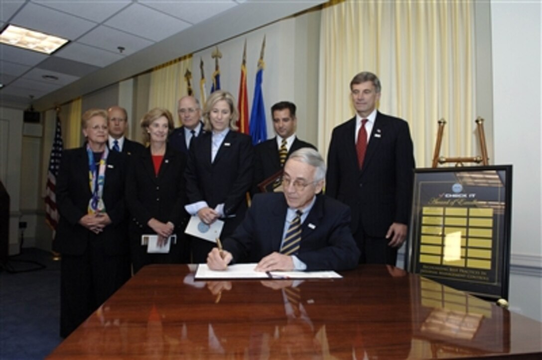 Deputy Secretary of Defense Gordon England signs the memorandum announcing the "Check It" Internal Management Controls Program Awareness Campaign Kickoff at the Pentagon on July 28, 2006.  Standing behind Secretary England are representatives from the Departments of the Air Force, Navy, and the Defense Logistics Agency who were recognized for the highest scores for fiscal year 2005 Statement of Assurance on Internal Management Controls.