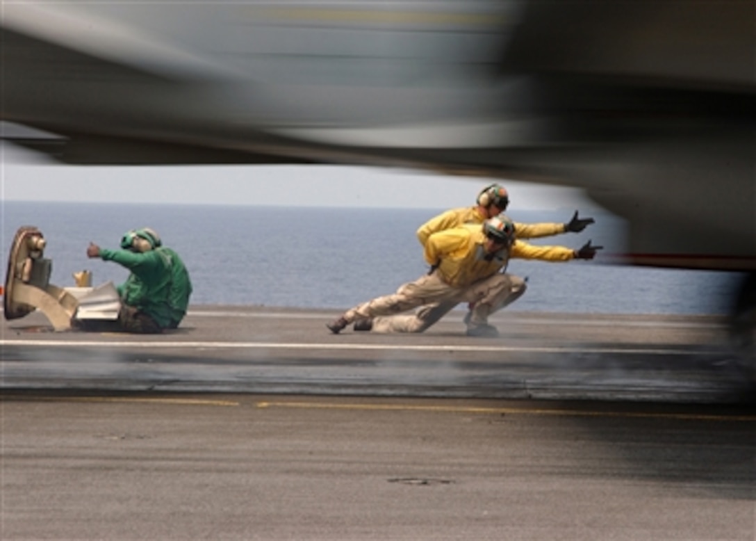 An F/A-18 Hornet accelerates past flight deck shooters aboard the aircraft carrier USS Theodore Roosevelt (CVN 71) as the ship conducts flight operations on July 24, 2006.  