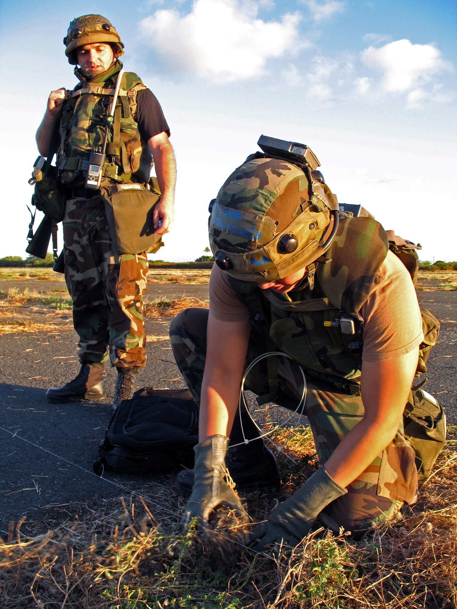 Chief Master Sgt. William Stumbo Jr. watches as Senior Airman Julius Valenzuela sets glow stick traps to warn of enemy intrusions during an exercise at Naval Station Barber's Point, Hawaii, on July 25. They are with the Hawaii Air National Guard's 297th Air Traffic Control Squadron. (U.S. Air Force photo/Tech. Sgt. Chris Vadnais) 
